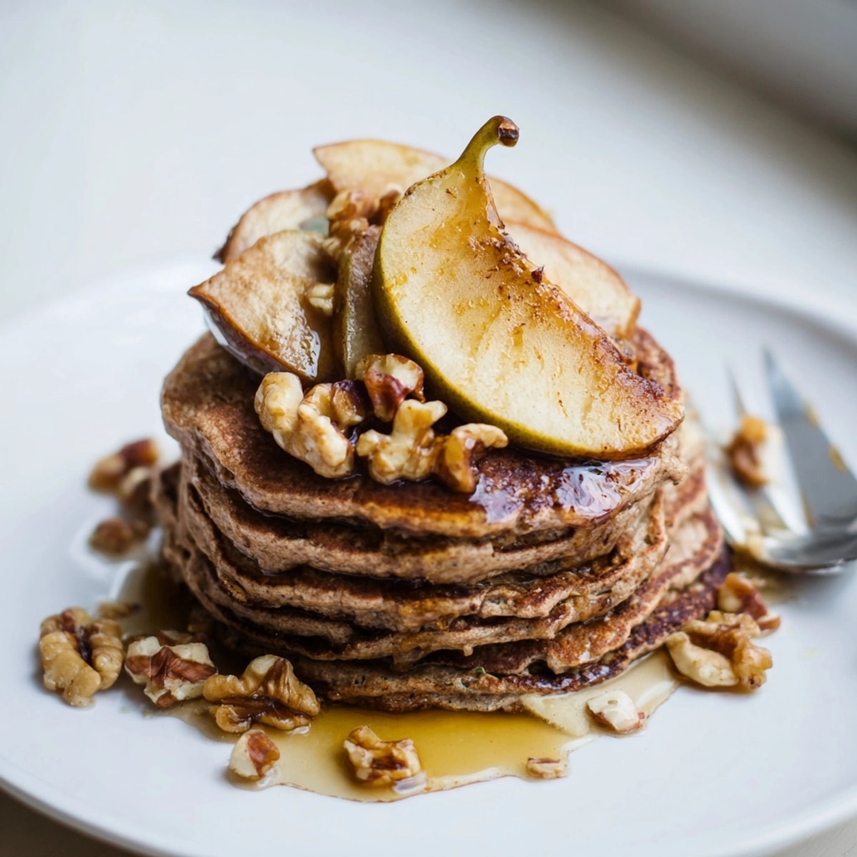 Warm, homemade buckwheat pancakes with roasted apple and cinnamon, drizzled with maple syrup.