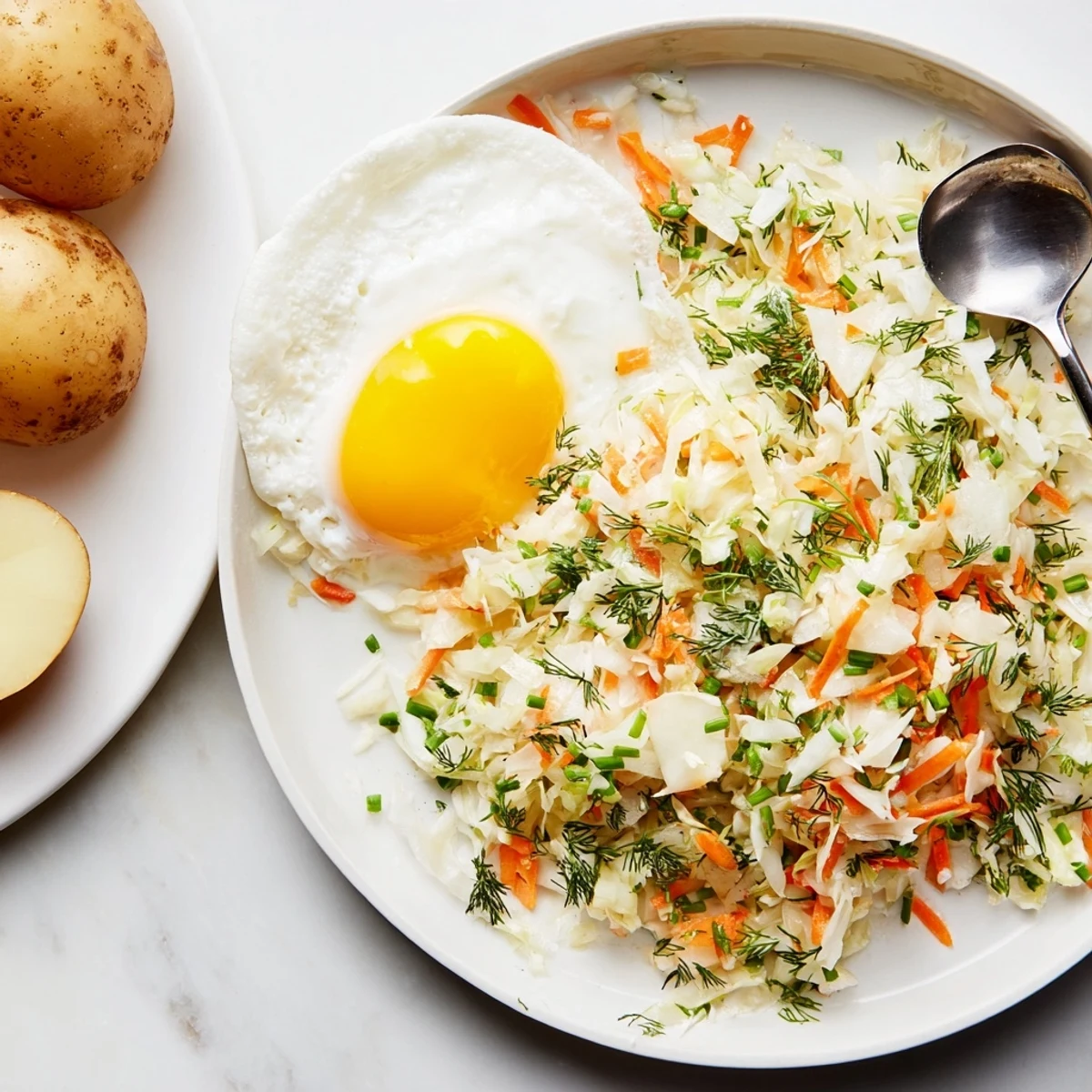 Vibrant Polish-style cabbage salad sits beside golden boiled potatoes and a fried egg.