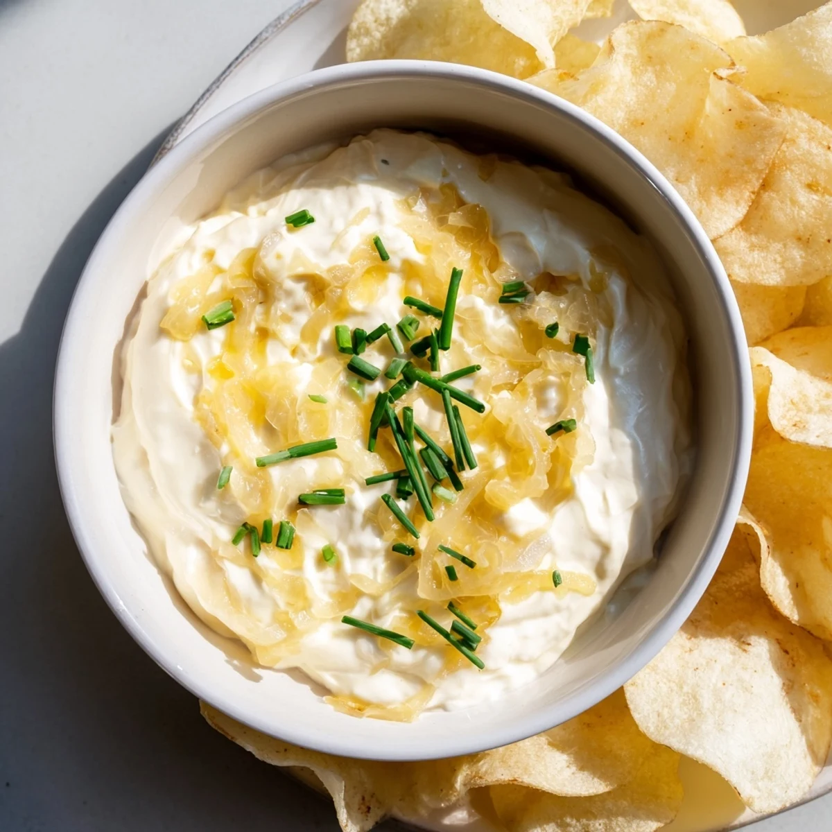 Close-up of a bowl filled with tasty, homemade onion dip served with crunchy potato chips.