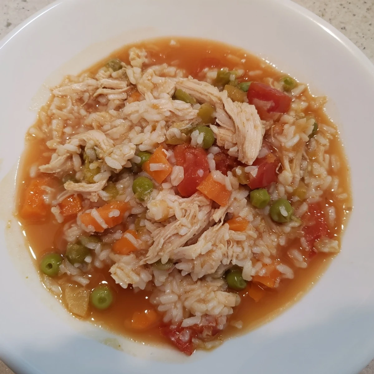 A steaming bowl of One-Pot Chicken and Rice, a comforting weeknight meal with colorful vegetables.