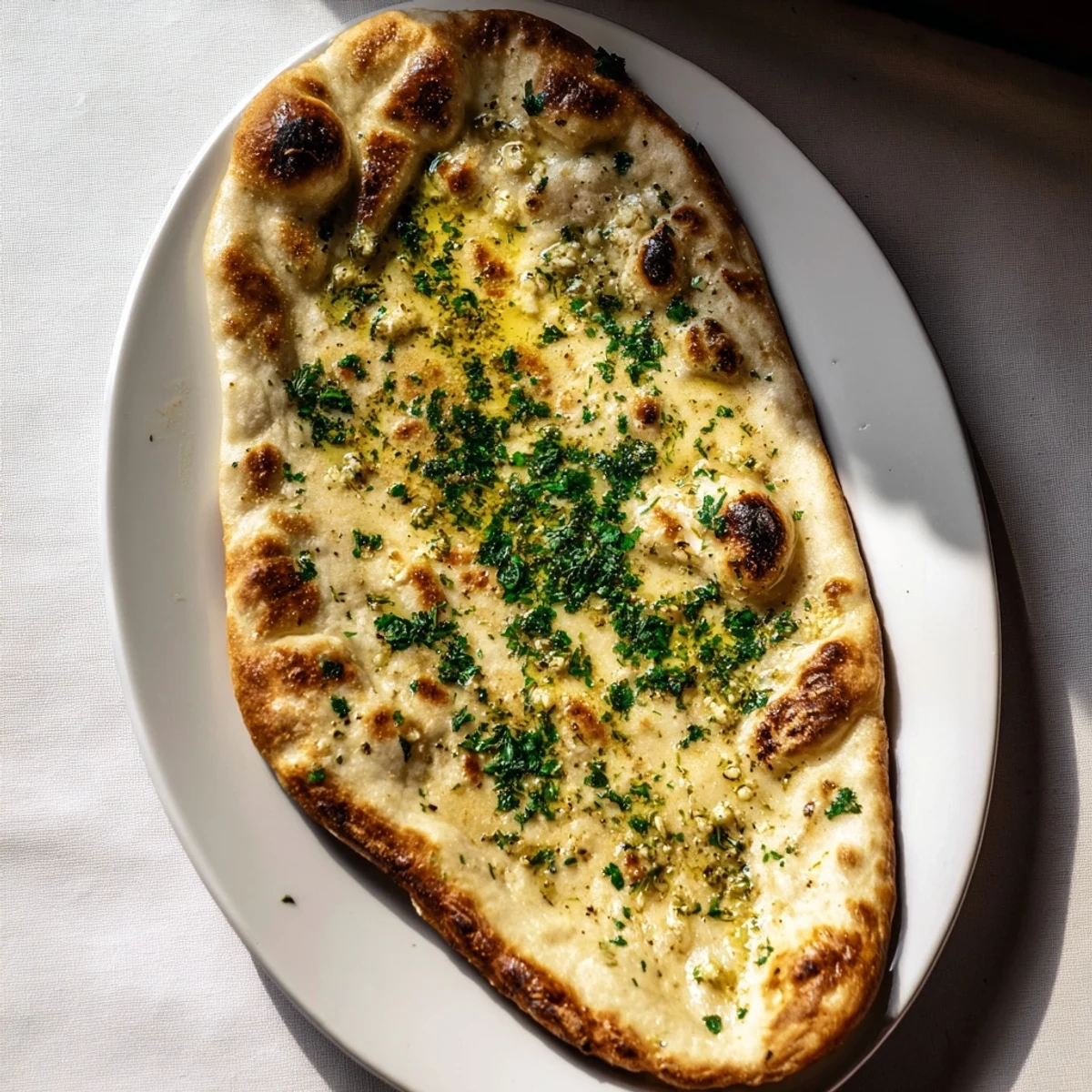 Freshly baked Homemade Garlic Naan Bread, crispy edges brushed with garlic butter, perfect with curry.