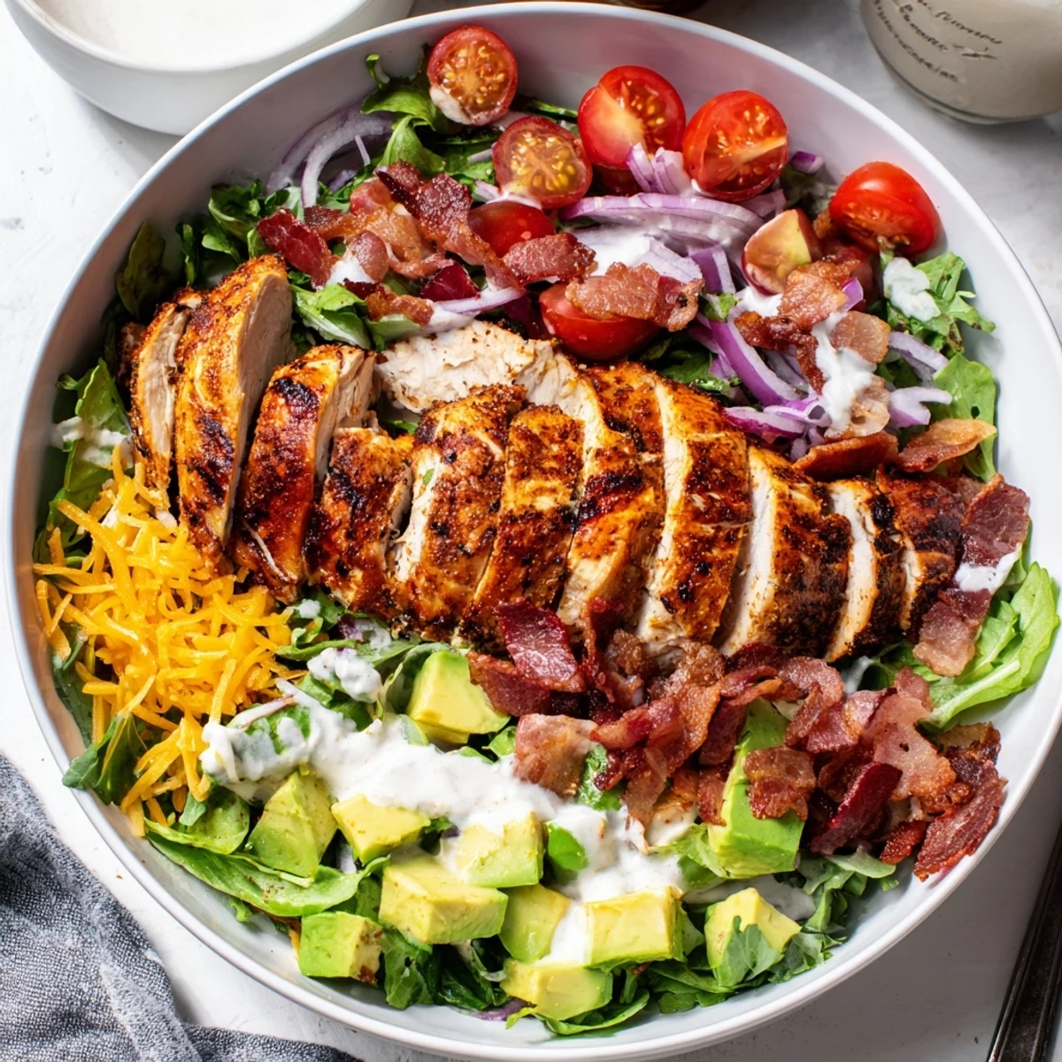 Crispy bacon chicken salad with vibrant greens, tomatoes, and creamy ranch dressing ready to eat.