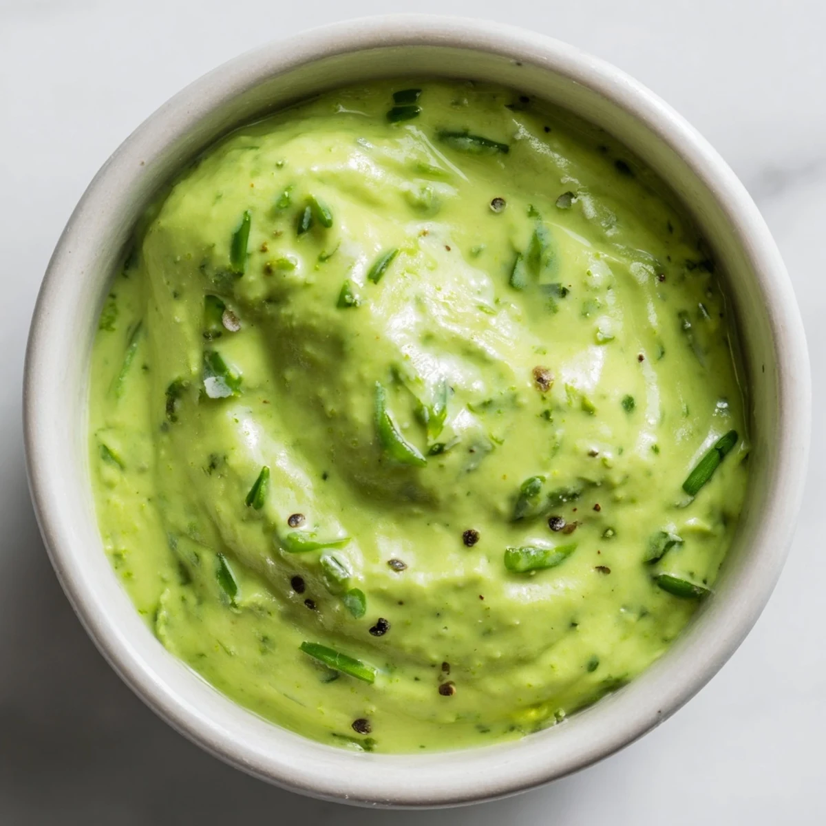 Creamy Green Goddess Dip with fresh herbs, ready to be scooped up with colorful, crisp vegetable sticks.