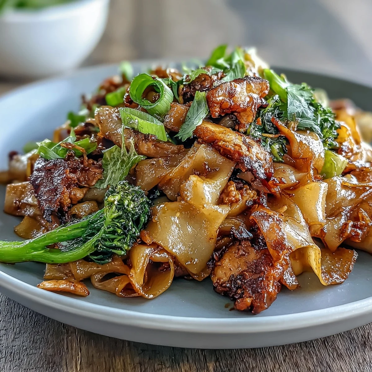 Sizzling Authentic Thai Pad See Ew steams from the wok, featuring glossy noodles, scrambled egg, and vibrant green gai lan for a street-food feel.