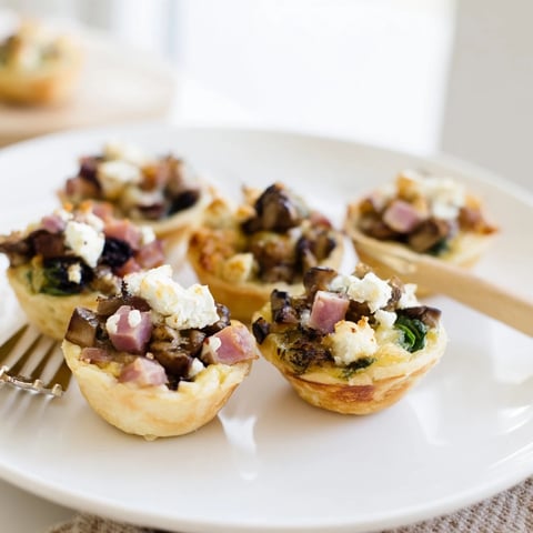 A holiday village board displays golden-brown mini quiches amongst festive decorations.