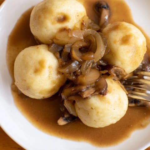 Pyszne Baked Potato Dumplings z aksamitnym sosem wegańskim aromatyzowane tymiankiem i szałwią gotowe do podania.