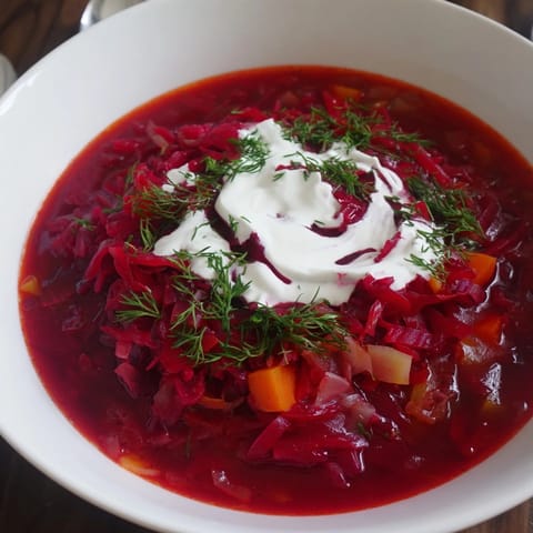 Kremowy czerwony barszcz z mleczkiem kokosowym w misce, wyraźne warstwy i para unosząca się ponad zupą.