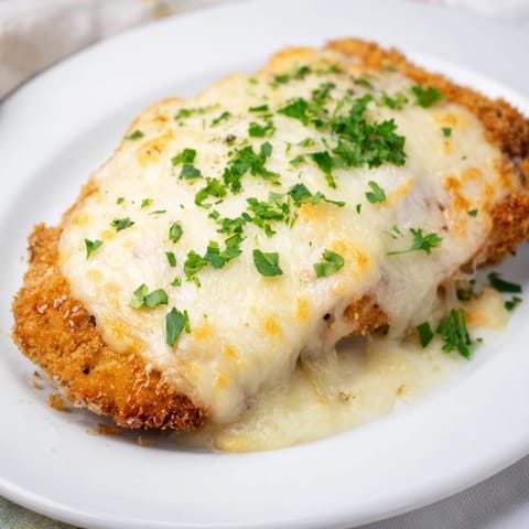 Złociste i chrupiące plastry schabowego zapieczone z serem, gotowe do podania z dodatkami.