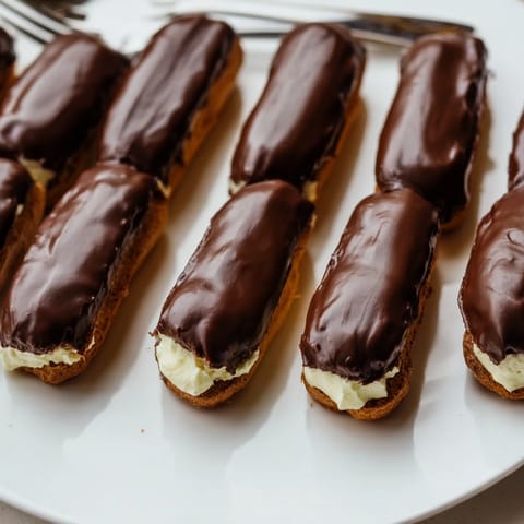 Poznaj apetyczne mini eklerki, każdy z pysznym kremem, a następnie polane czekoladą.