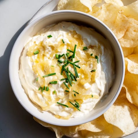 Close-up of a bowl filled with tasty, homemade onion dip served with crunchy potato chips.