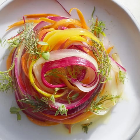 Vibrant "Spinning Top" salad with wispy vegetables, herbs, ready to be drizzled with dressing.