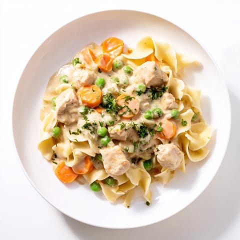 A steaming bowl of Creamy Chicken and Egg Noodles, topped with fresh parsley for serving.