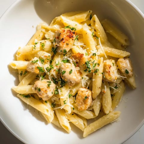 Golden chicken bites and pasta tossed in creamy Quick Garlic Parmesan Chicken Pasta sauce, garnished with parsley.