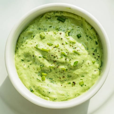 Vibrant green Green Goddess Dip, a party favorite, served alongside crunchy tortilla chips for dipping.