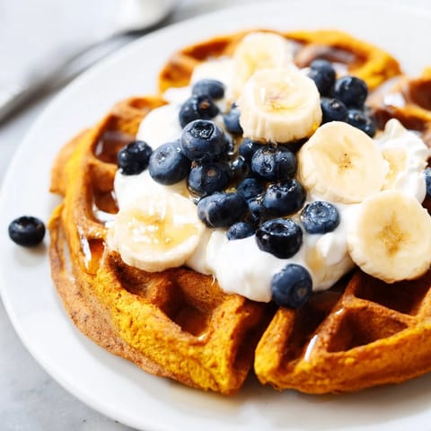 Złociste, puszyste gofry z kurkumą i adaptogennymi przyprawami, podane z jogurtem i świeżymi owocami.