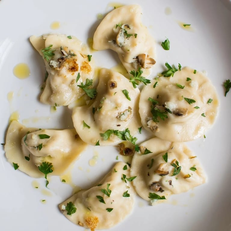 Gotowe pierogi z dzikimi grzybami i truflowym olejem, z apetycznie zarumienioną skórką i kremowym nadzieniem.