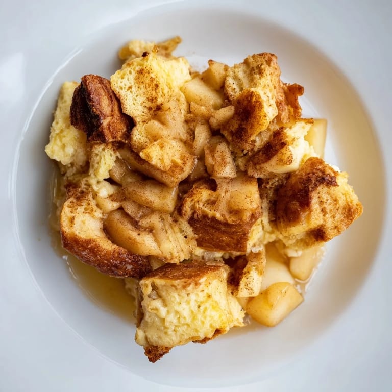 Golden-brown bread pudding with apples and cinnamon, perfect for a cozy dessert, served warm.
