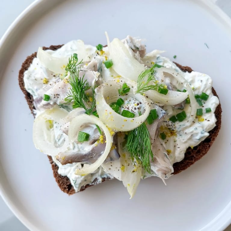 Apetyczny widok: świeży śledź Cream Cheese Tartine gotowy do spożycia, ze świeżym koperkiem i skórką z cytryny.