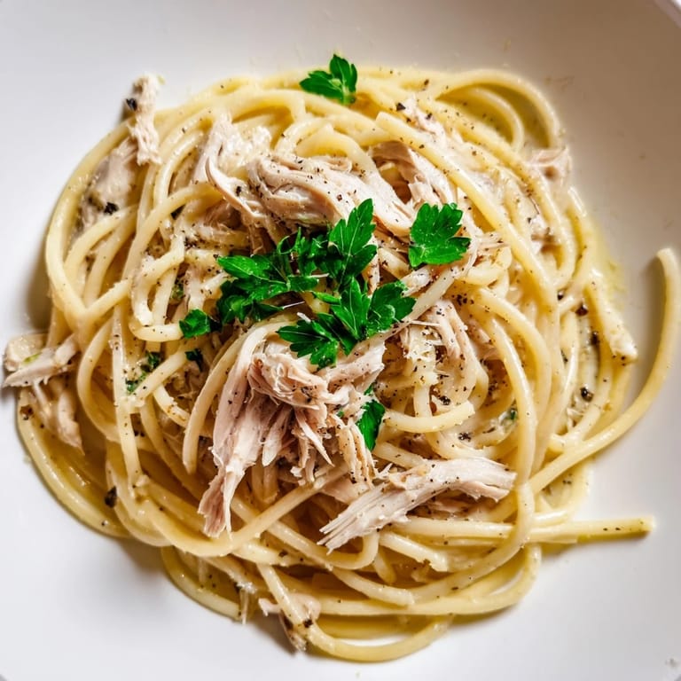 Zdjęcie przedstawia apetyczne, proste bucatini z czosnkowym masłem i delikatnym kurczakiem.