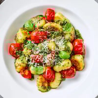 Golden, crispy gnocchi with pesto, cherry tomatoes, and Parmesan promise a flavorful Italian dinner.
