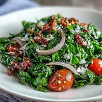 Dandelion Greens Salad with Lemon Vinaigrette and Parmesan, vibrant and fresh, topped with shaved cheese and toasted pine nuts.  