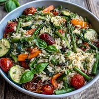 Orzo Primavera z kolorowymi warzywami, gotowe do podania na wiosennym obiedzie.